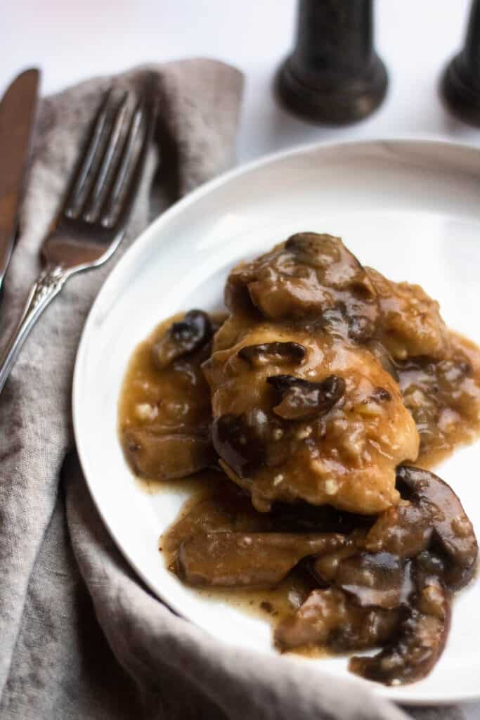 plate of chicken marsala with a fork  and a napkin next to it 