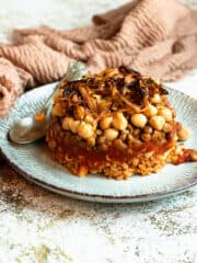 Koshari on a plate topped with tomato sauce, chickpeas, fried onions and pasta.