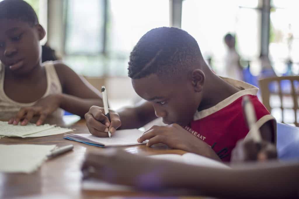 A kid writing on a desk.