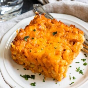 Slice of macaroni pie on a plate with a fork resting on the side.