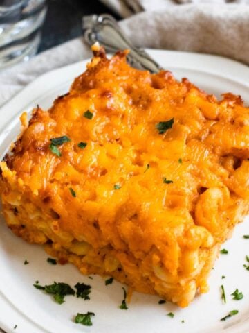 Slice of macaroni pie on a plate with a fork resting on the side.