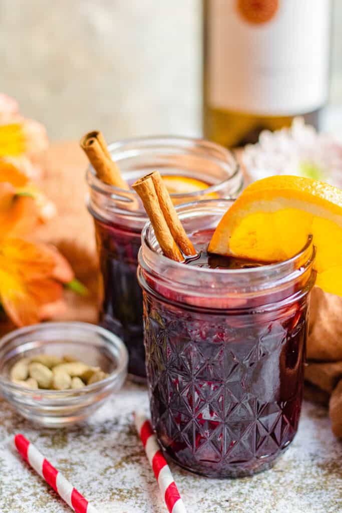 Mulled wine in mason jars with cinnamon bark, oranges, and cardamom pods 