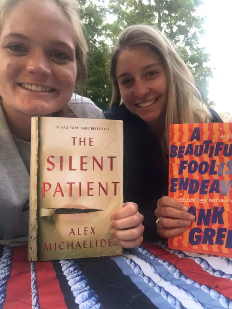 Alexandria and elizabeth taking a selfie with their books.