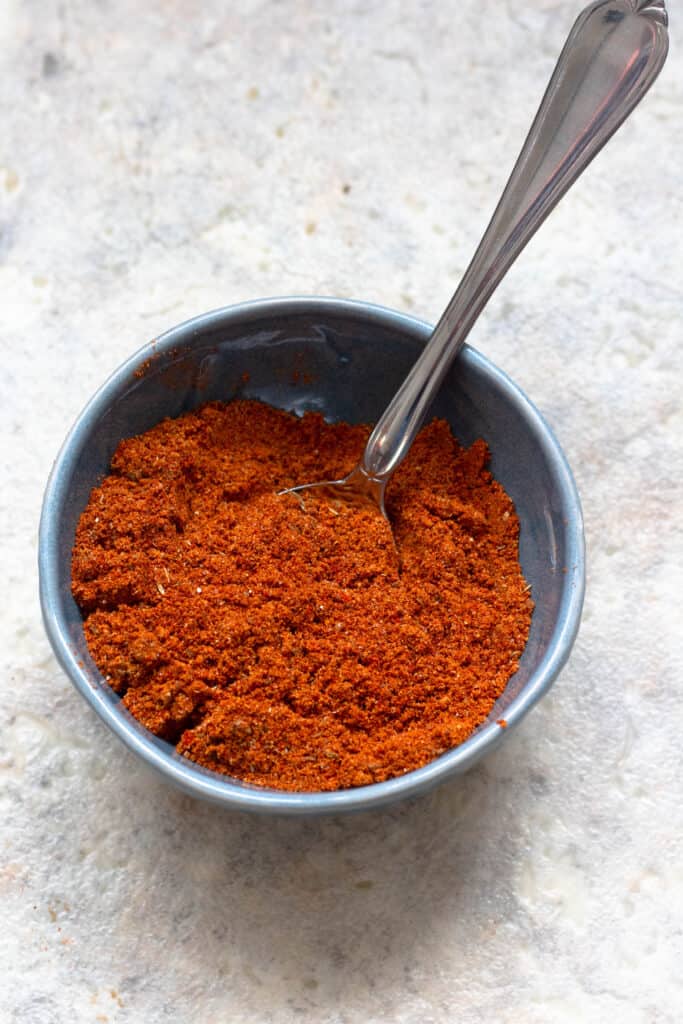 Berbere spices in a blue bowl with a spoon 