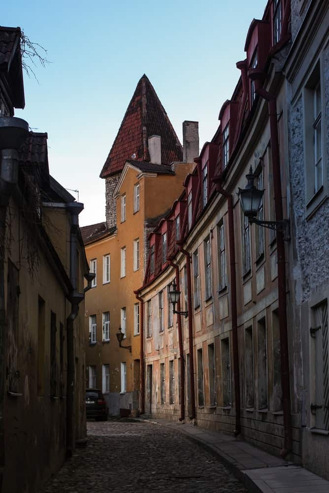 a cobblestone lined alley with different colored buildings lining the street.