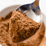 Pinterest image of a spoonful of the baharat spice blend.