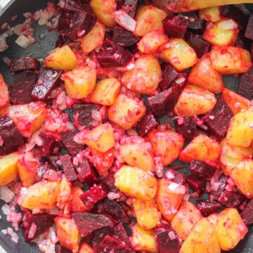 Beet and Potato salad in a large pan with a wooden spoon.