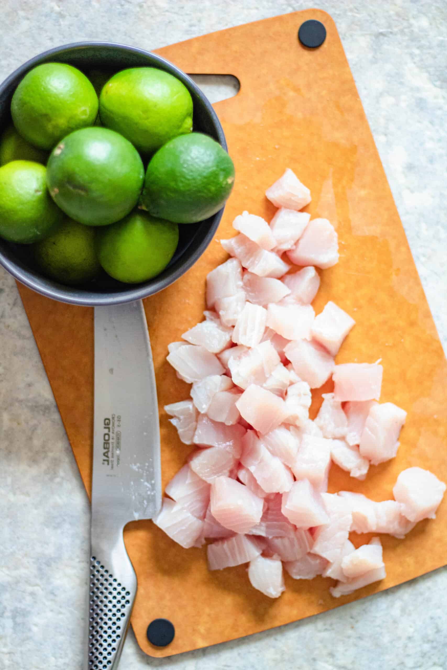 Whole limes and chunks of white fish used to prepare ceviche. 