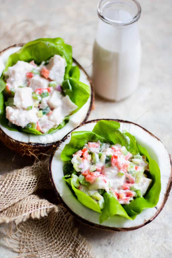 Coconut bowl filled with green lettuce and cooked ceviche in coconut milk 