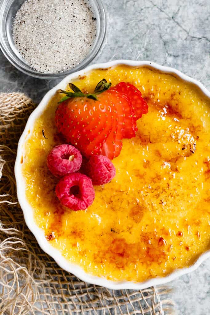close up of scalloped bowl with creme brulee and a bowl of sugar 