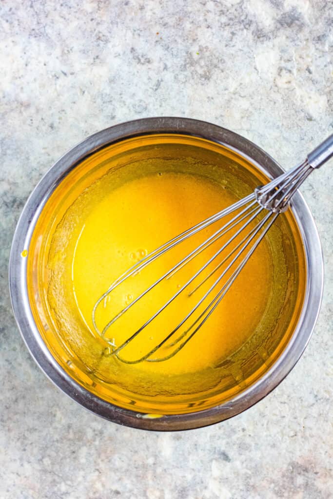 mixing bowl with whisked egg yolks and a whisk 