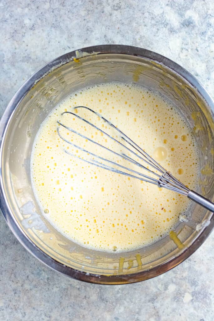 mixing bowl with uncooked custard and a whisk 