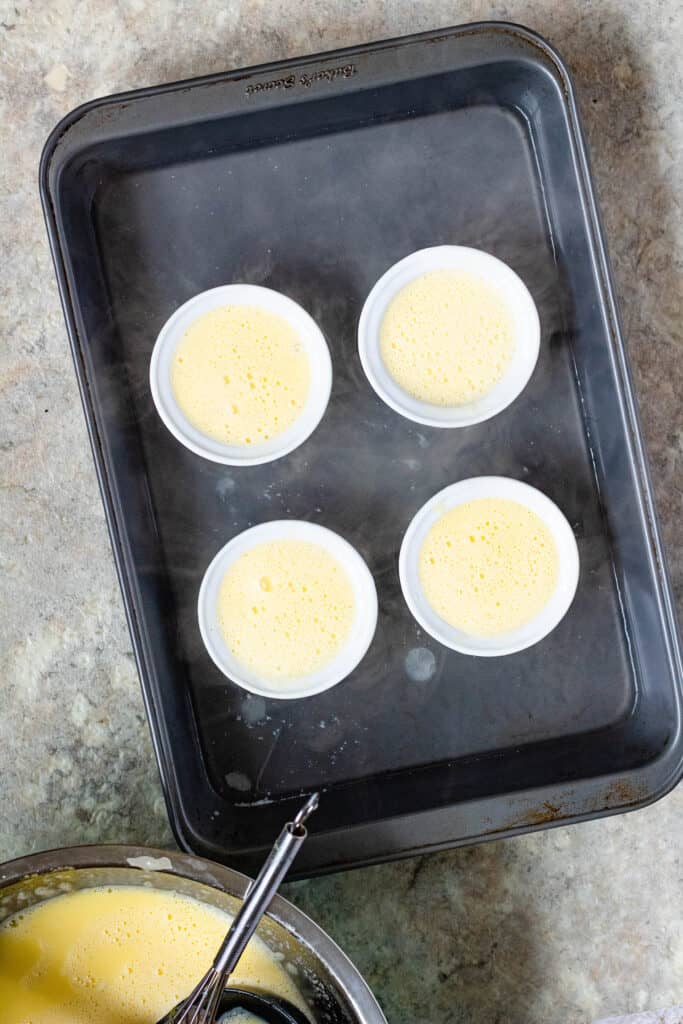 ramekins with uncooked custard in a 9x13 nonstick pan and surrounded by water