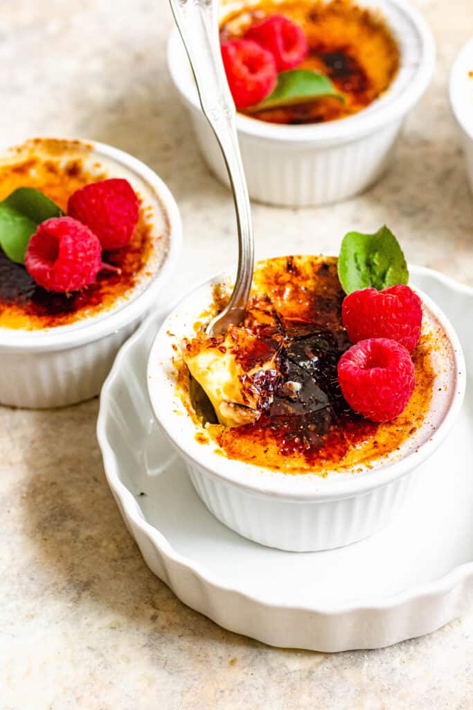 small ramekin of creme brulee with raspberries and a cracked top 