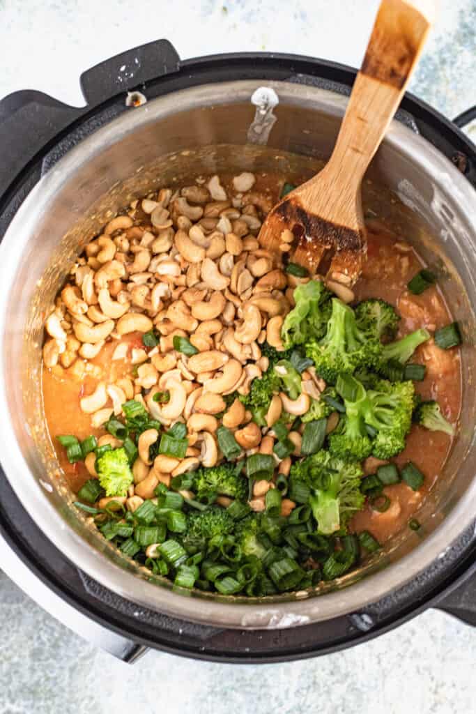 Adding broccoli, cashew chicken, and green onions in the instant pot