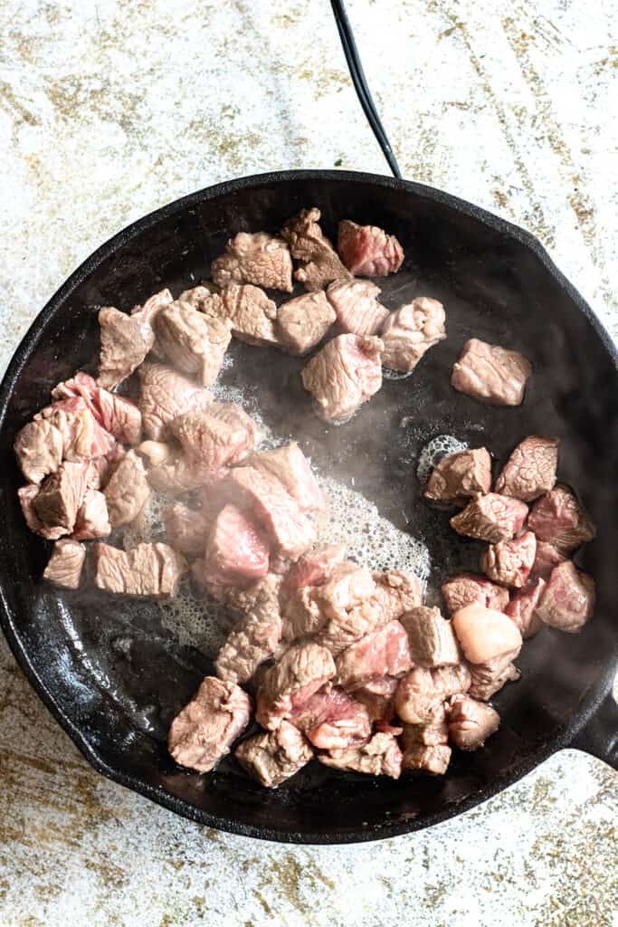 steak cooking in a cast iron skillet