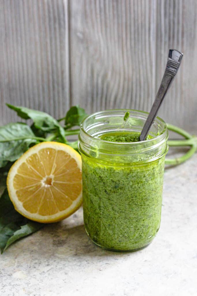 glass jar with easy pesto recipe and a lemon behind it