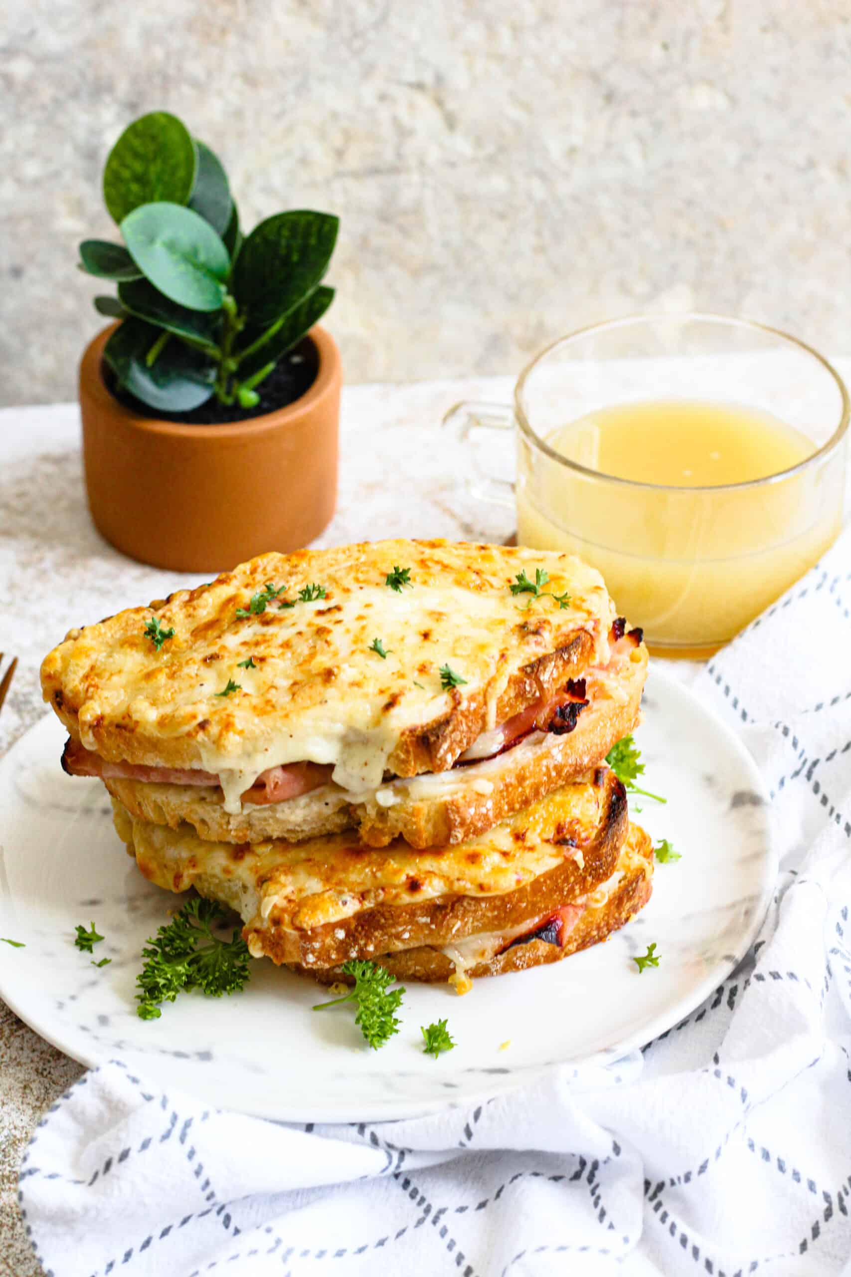 A croque monsieur sandwich on a plate with a glass of orange juice. 
