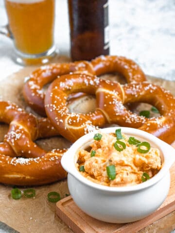 German Obatzda in a serving platter sitting in front of German soft pretzels.