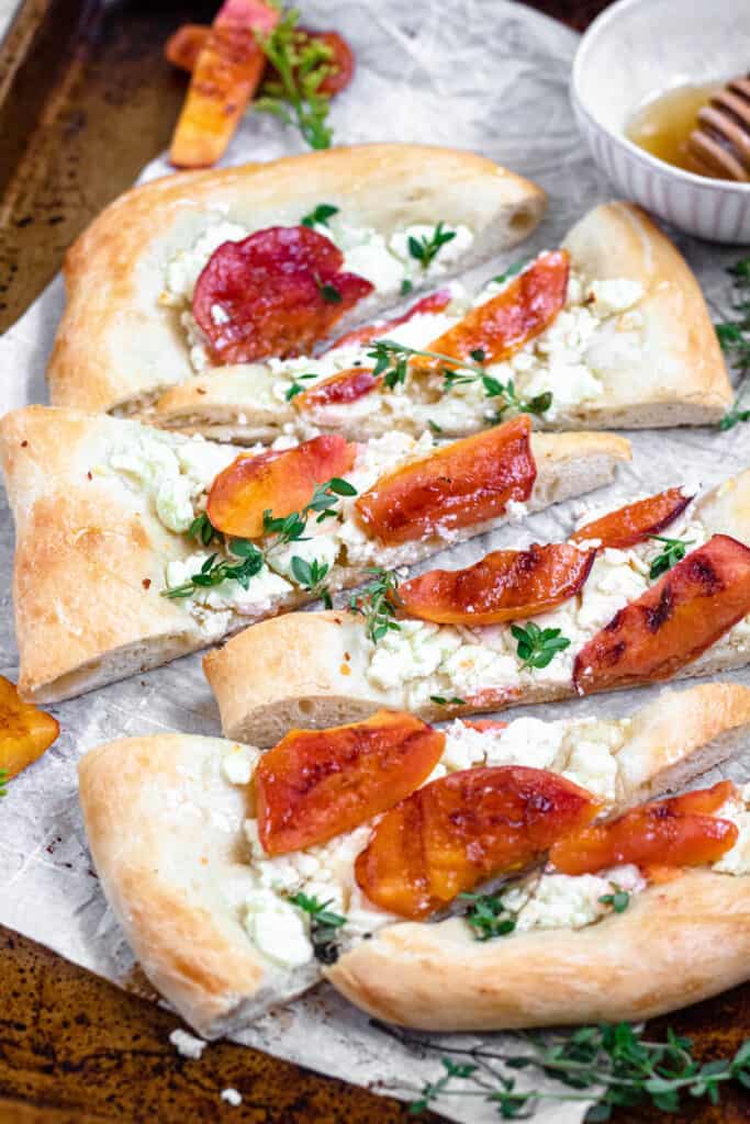 Sliced peach pizza with herbs and cheese on it