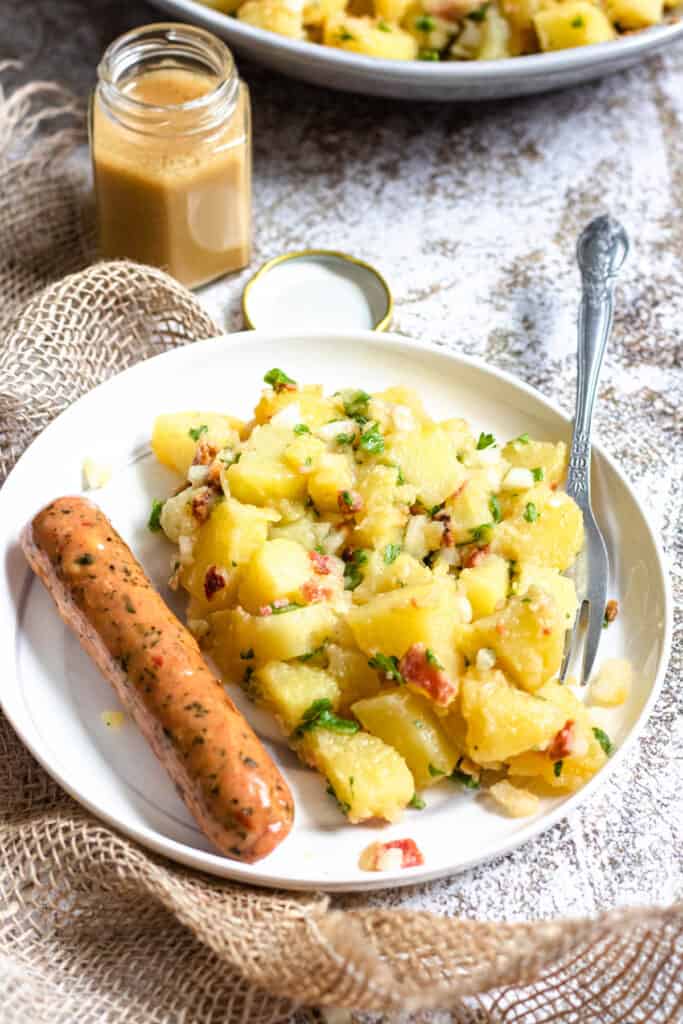 plate of german potato salad with a sausage on the side