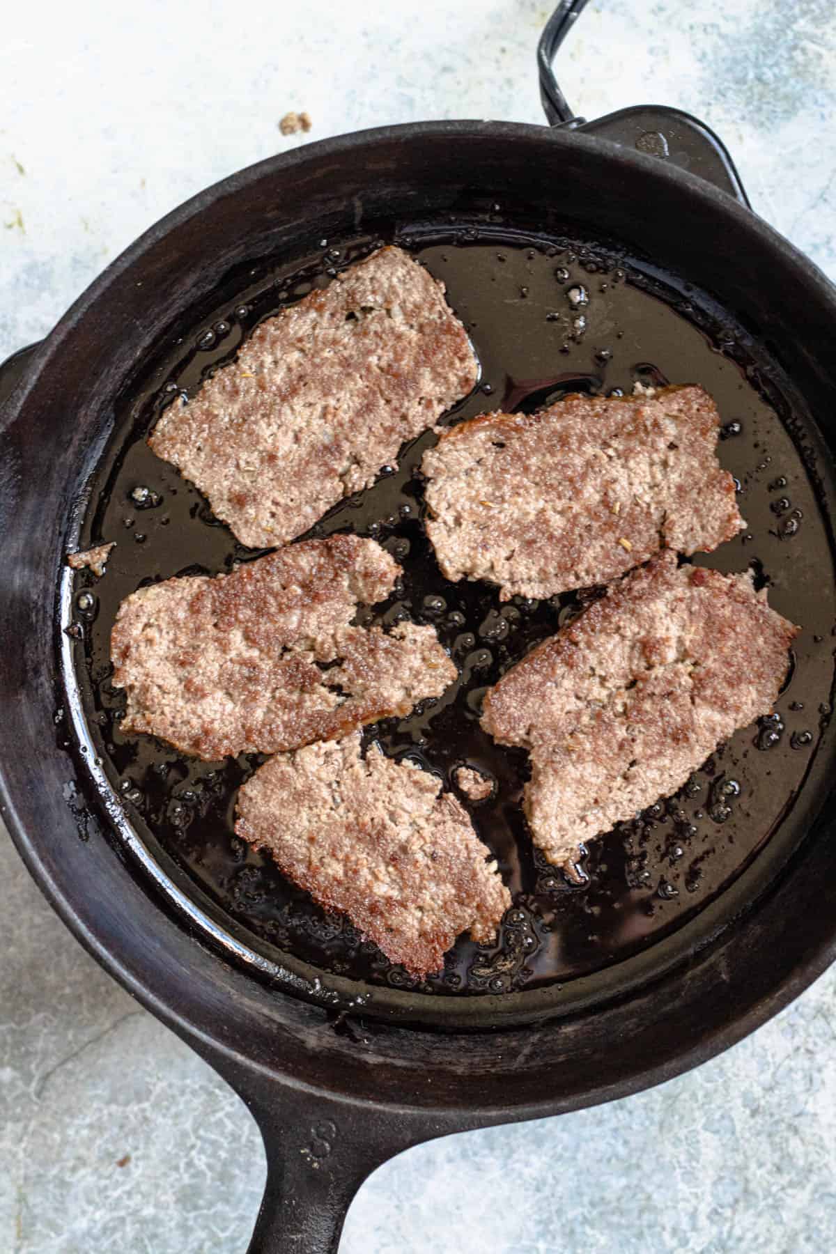 Cast iron pan showing slices of gyro meat. 