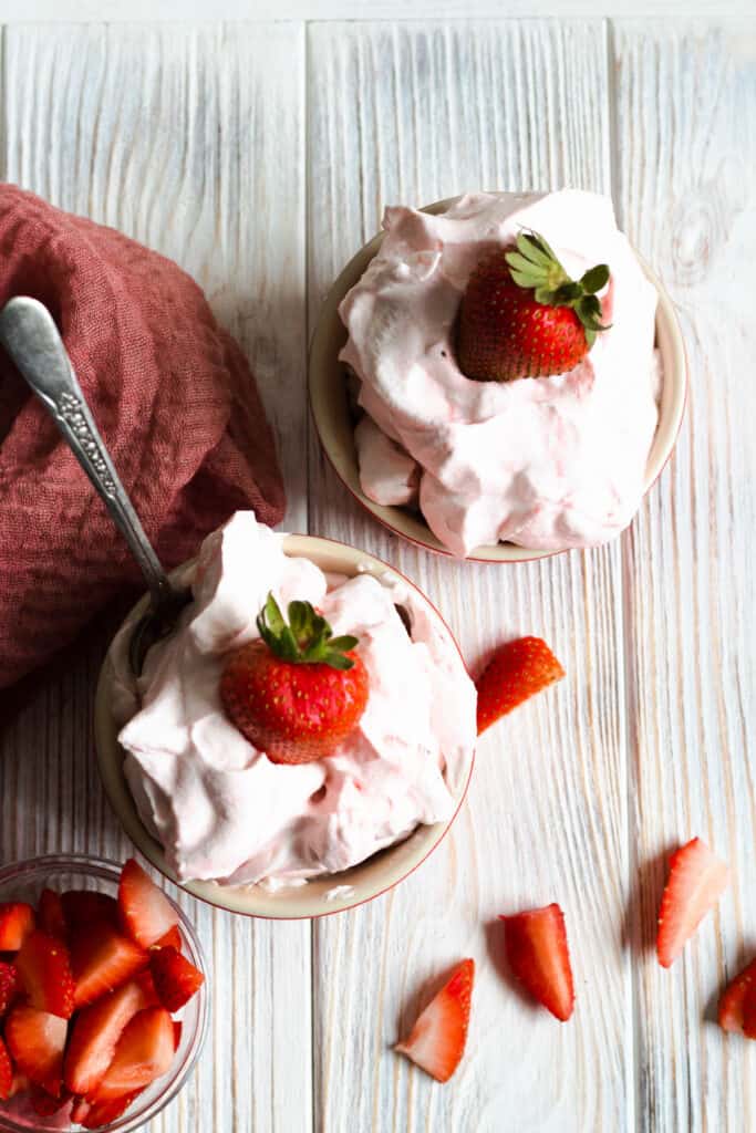 overhead of 2 small bowls of cream with strawberry topping