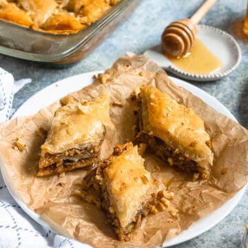 Pistachio and walnut baklava cut into triangles on a white plate.
