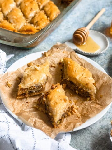 Pistachio and walnut baklava cut into triangles on a white plate.