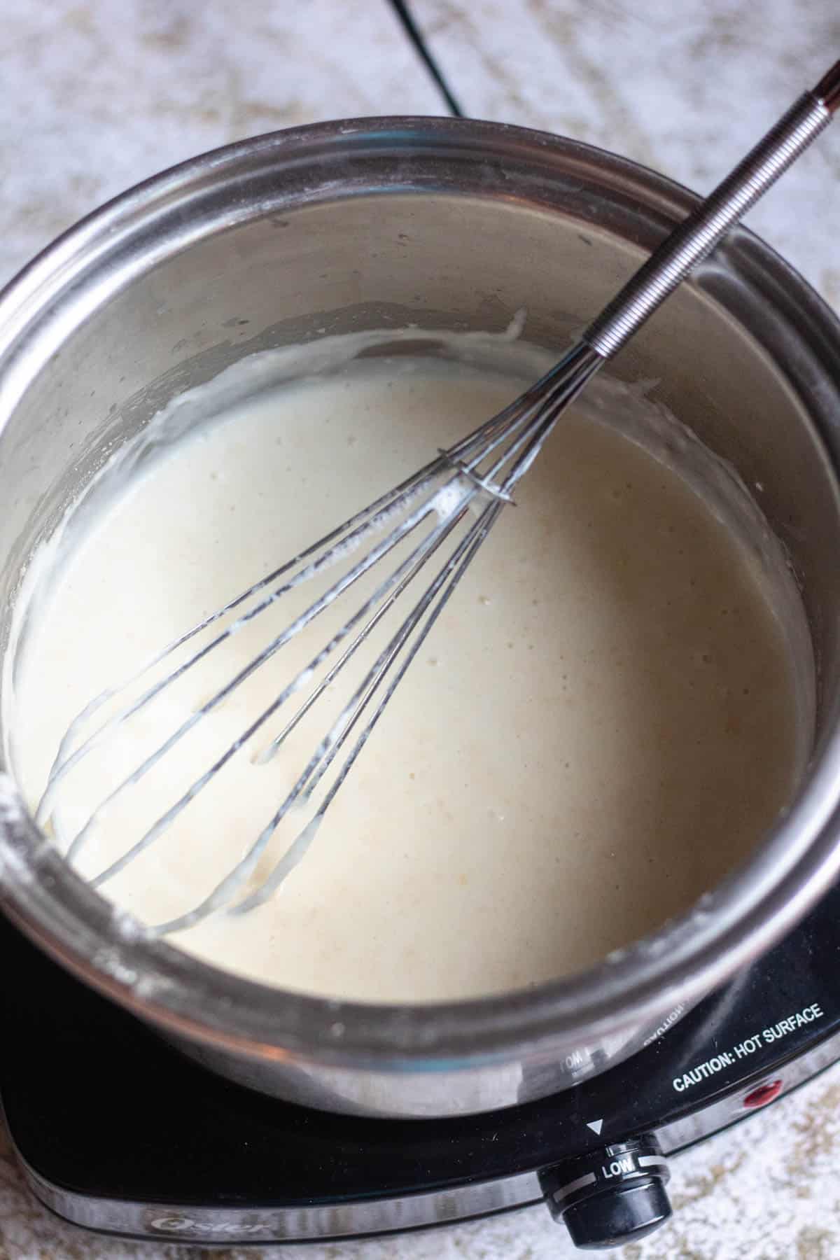 pot of béchamel with a whisk in it