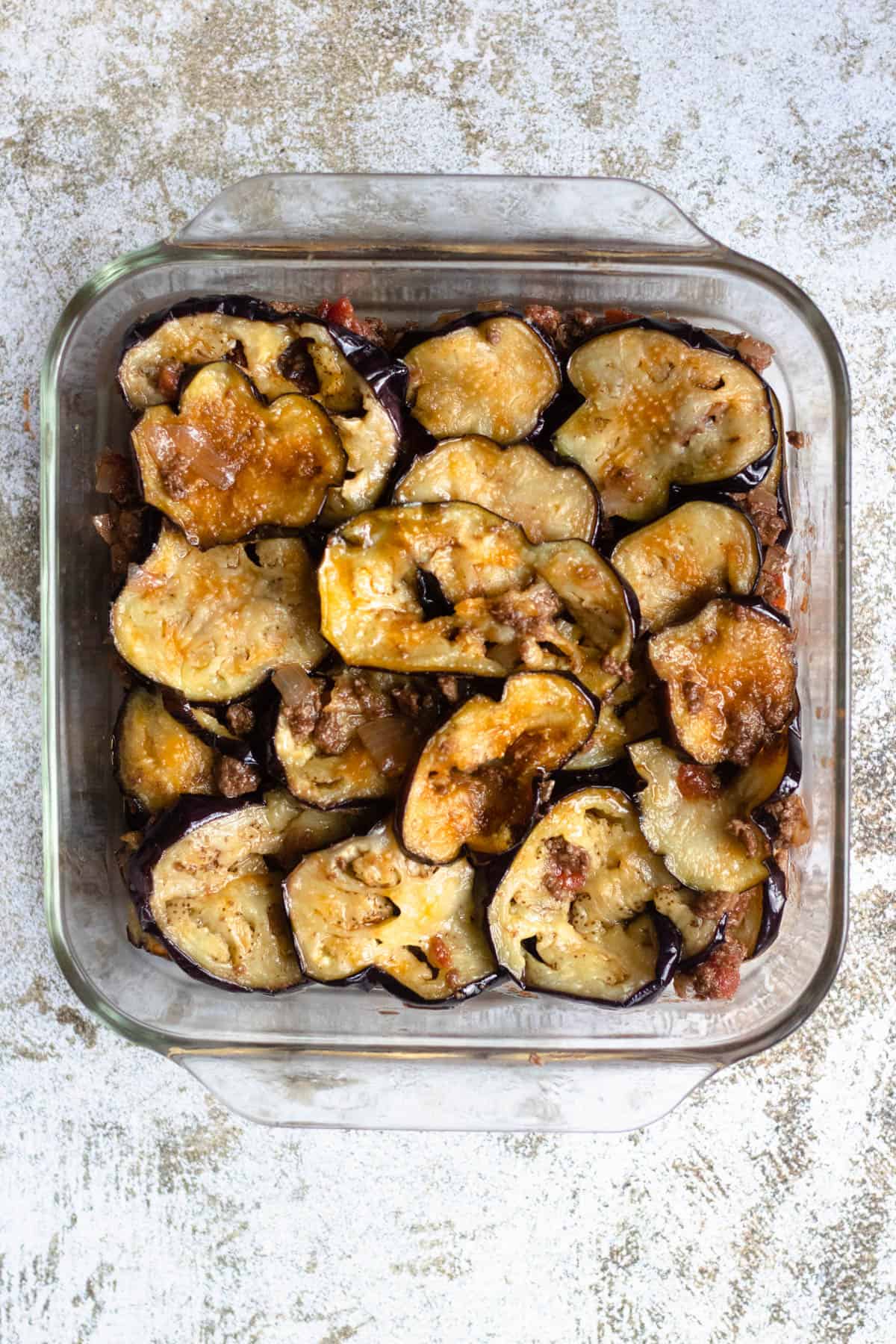 fried eggplants layered in an 8x8 casserole dish