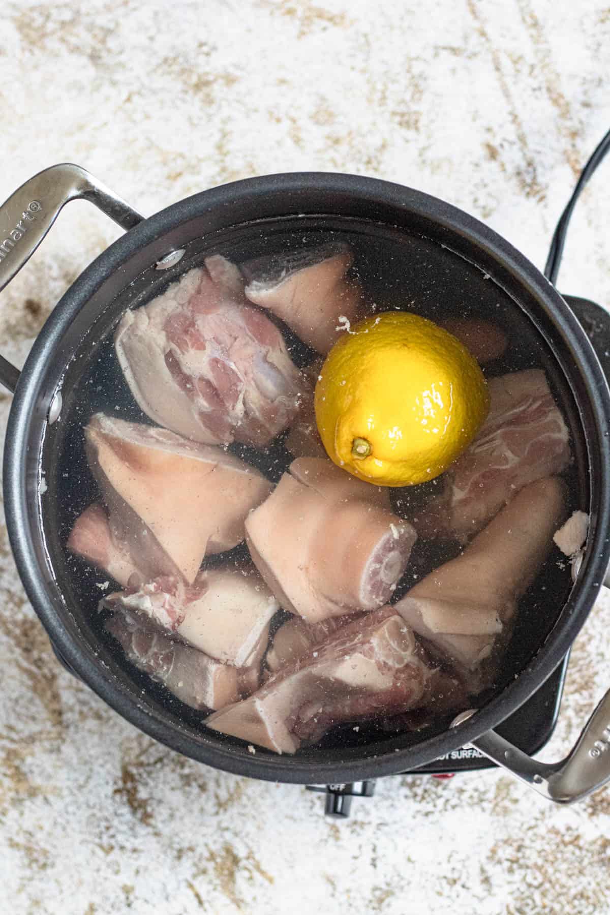 A pot with boiling cows tails and a half of a lemon.
