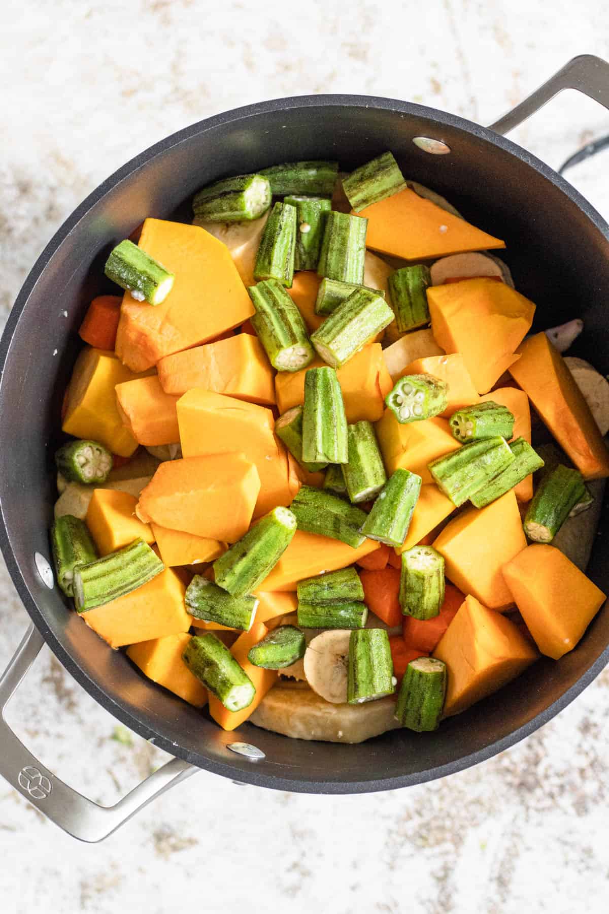 Oil Down in a pot with pumpkin and okra on top 