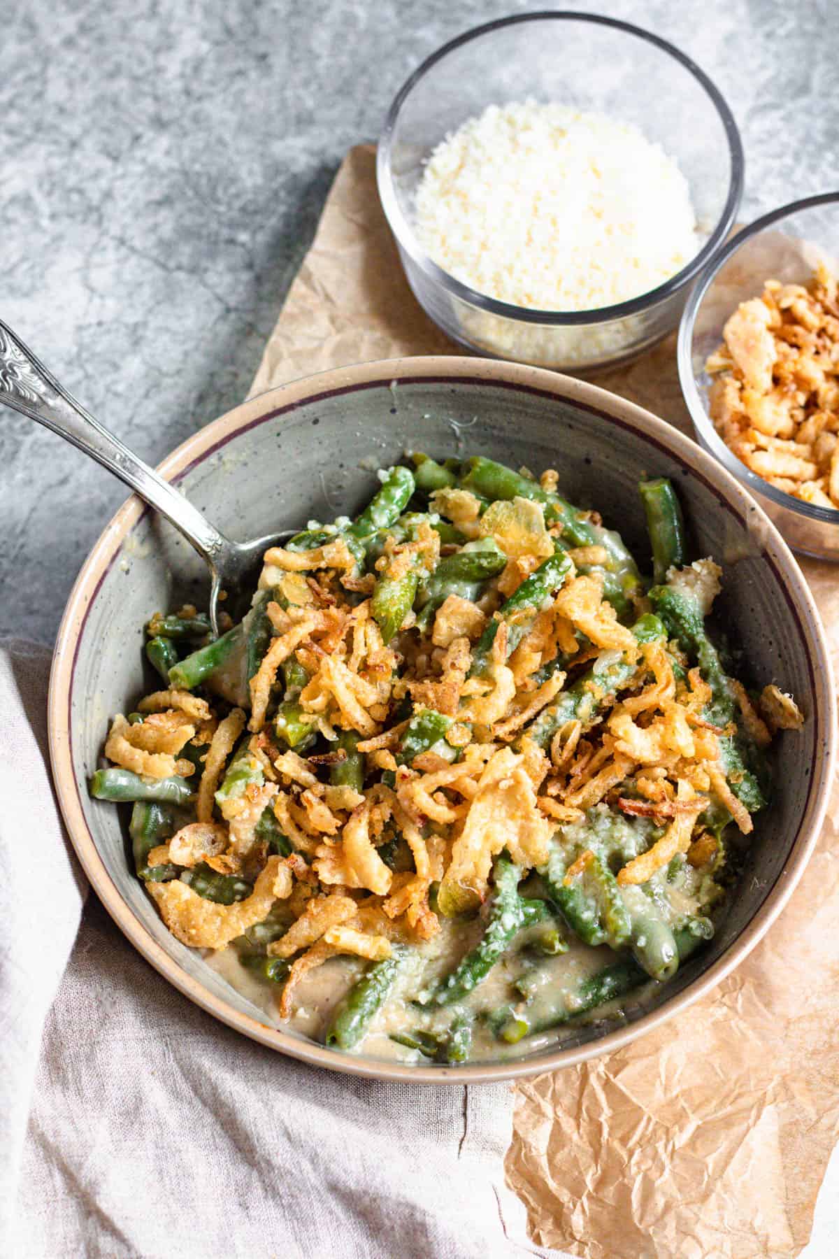 Bowl of instant pot green bean casserole with fried onions on top and on the side 