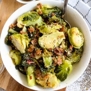 Brussels Sprouts with bacon and topped with parmesan cheese in a bowl.