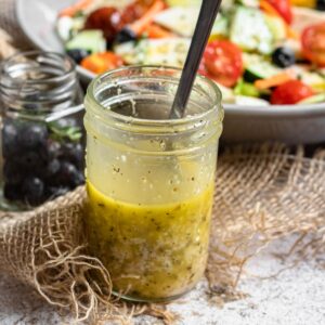 Italian dressing in a mason jar in front of a salad.