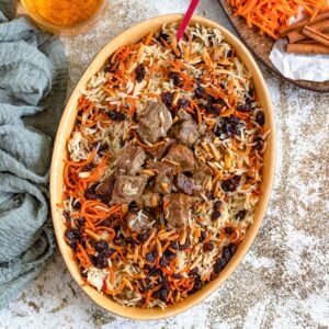 Top view of a bowl of Kabuli Pulao topped with tender pieces of beef and plump raisins.