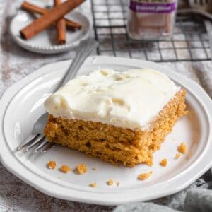 Pumpkin cake with cream cheese frosting served on a small white plate.