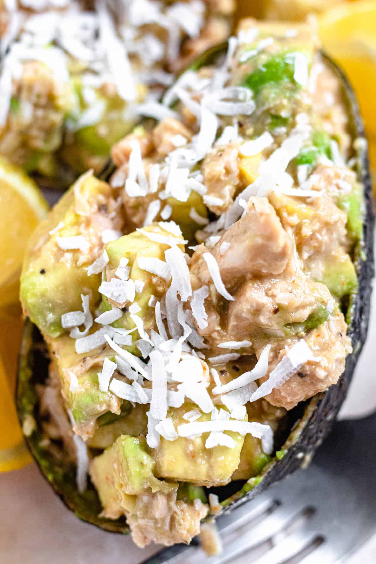 close up of ½ of an avocado stuffed with tuna, coconut, and sauce