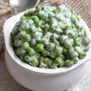 A serving crock filled with Instant Pot Creamed Peas.