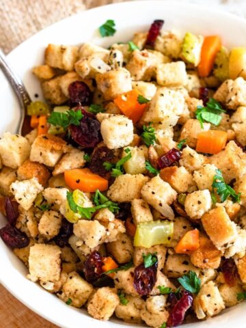 A bowl of bread stuffing with craisins, carrots, and herbs.