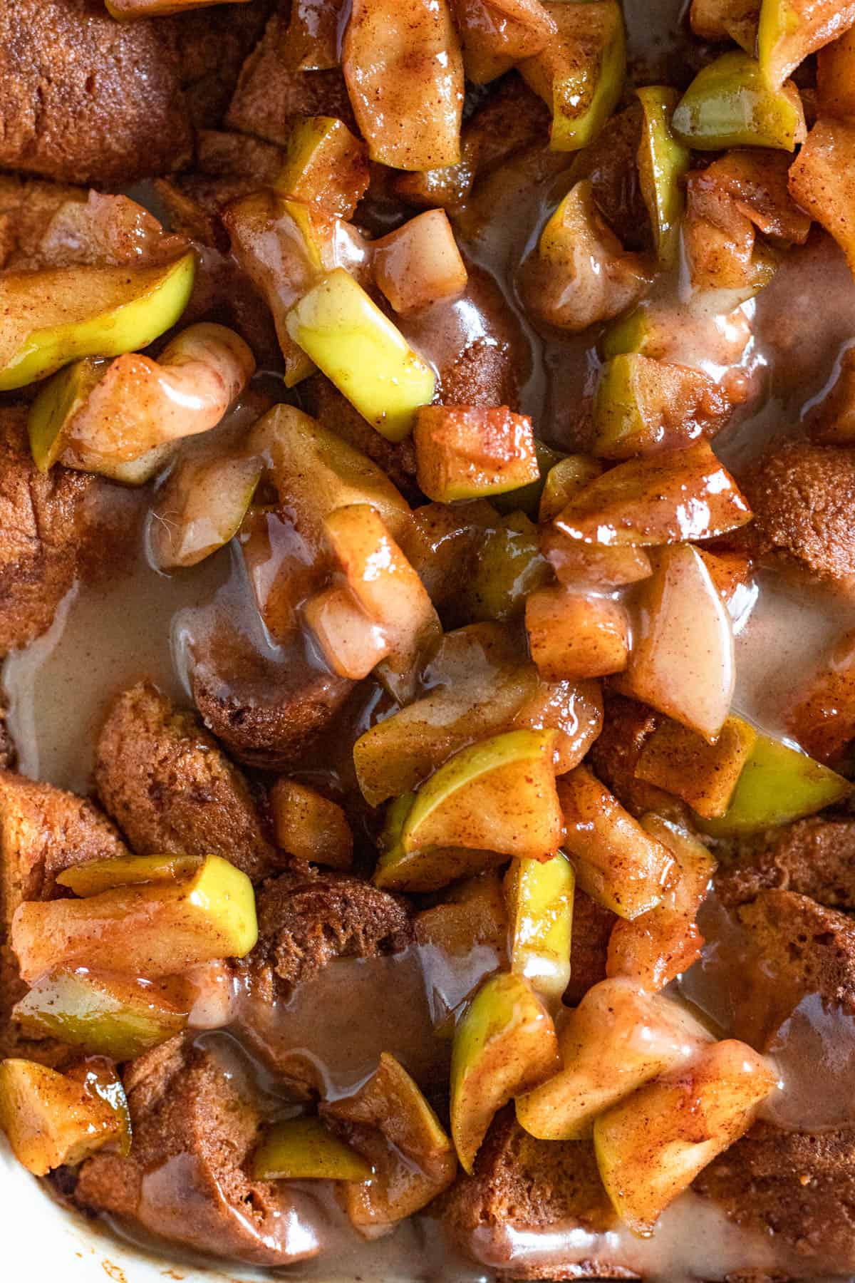 Close up of apple cider donut bread pudding with apples and vanilla sauce