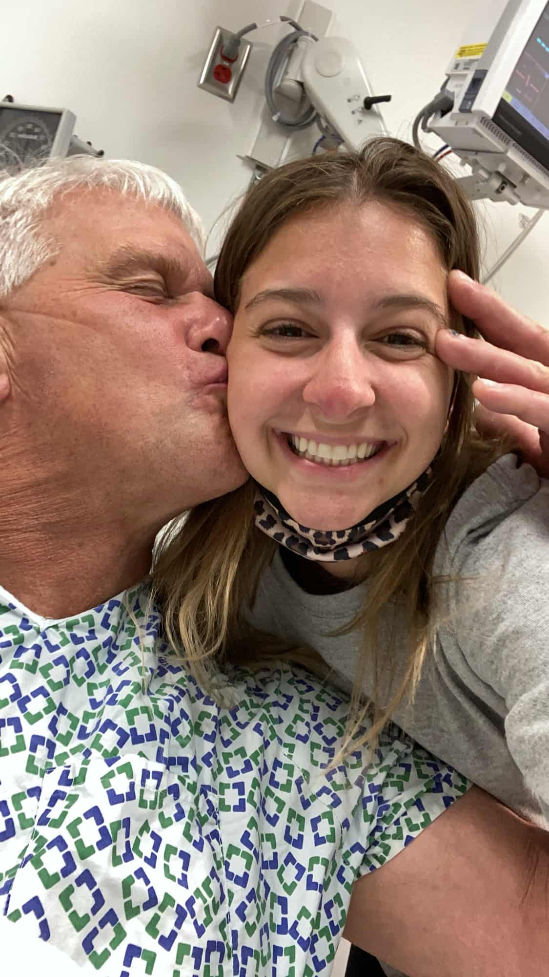 A man kissing a woman on the cheek while in the hospital. 