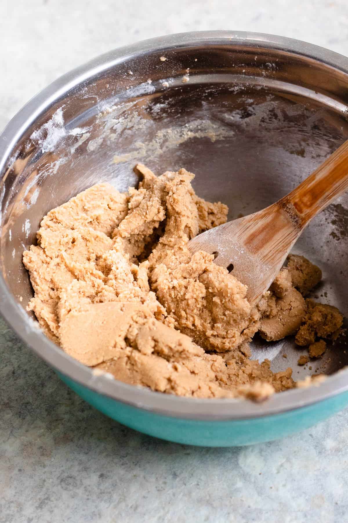 Cookie dough in a mixing bowl with a wooden spoon