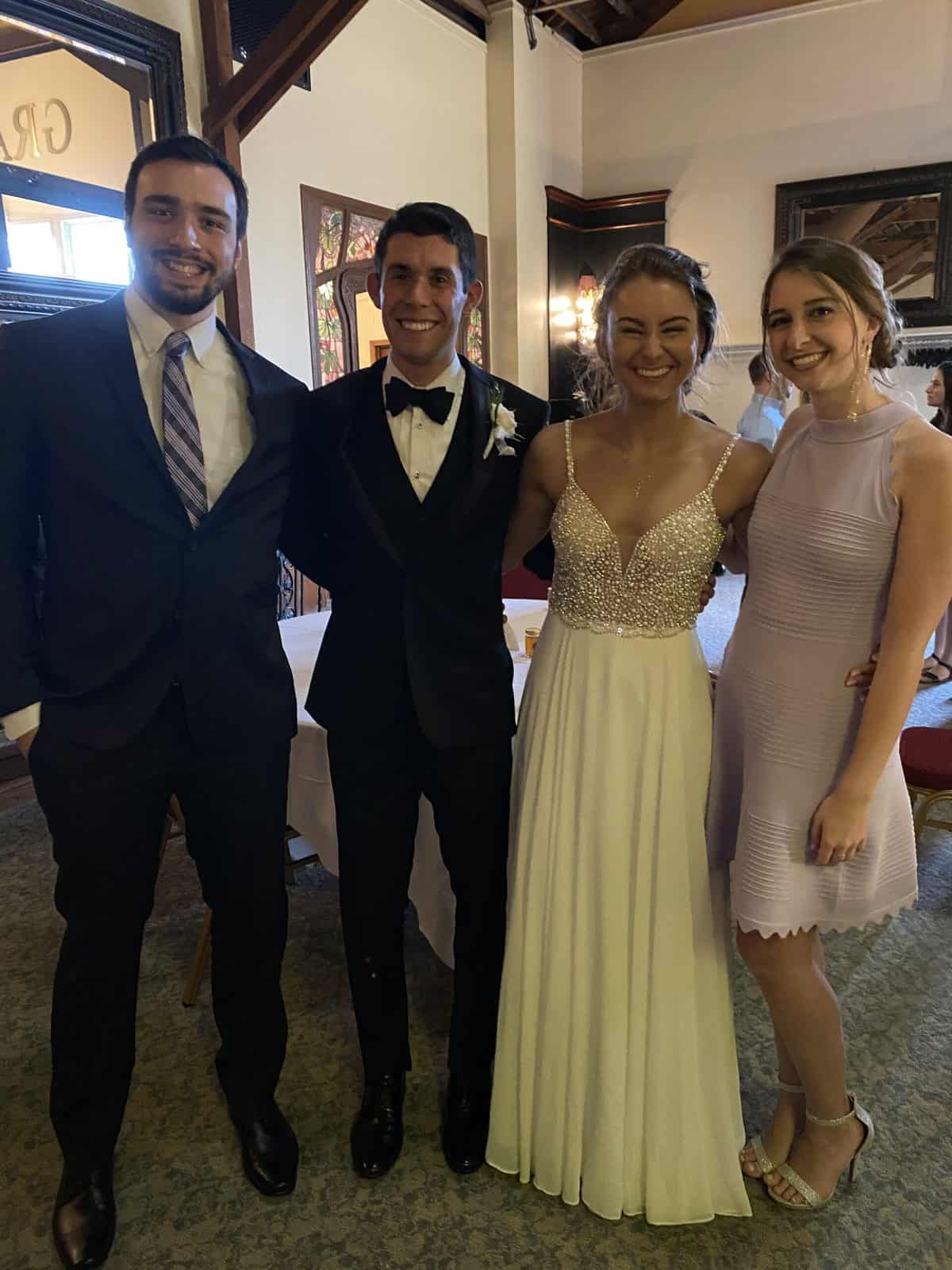 A bride and groom posing with two wedding guests.
