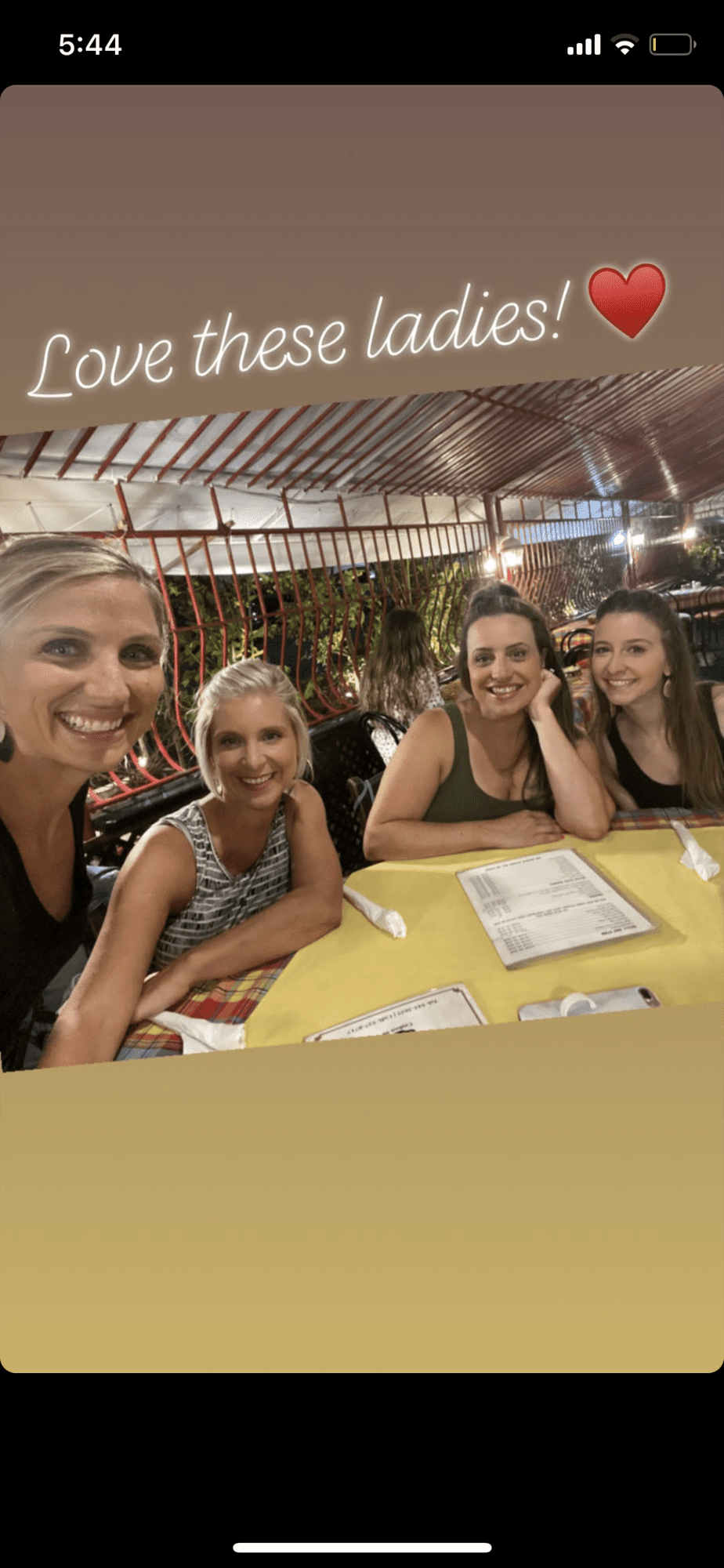 Four women smiling at a restaurant table.