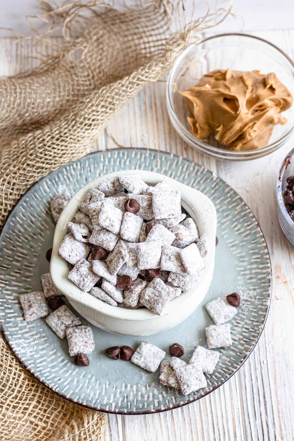Bowl of puppy chow on a plate sprinkled with chocolate chips