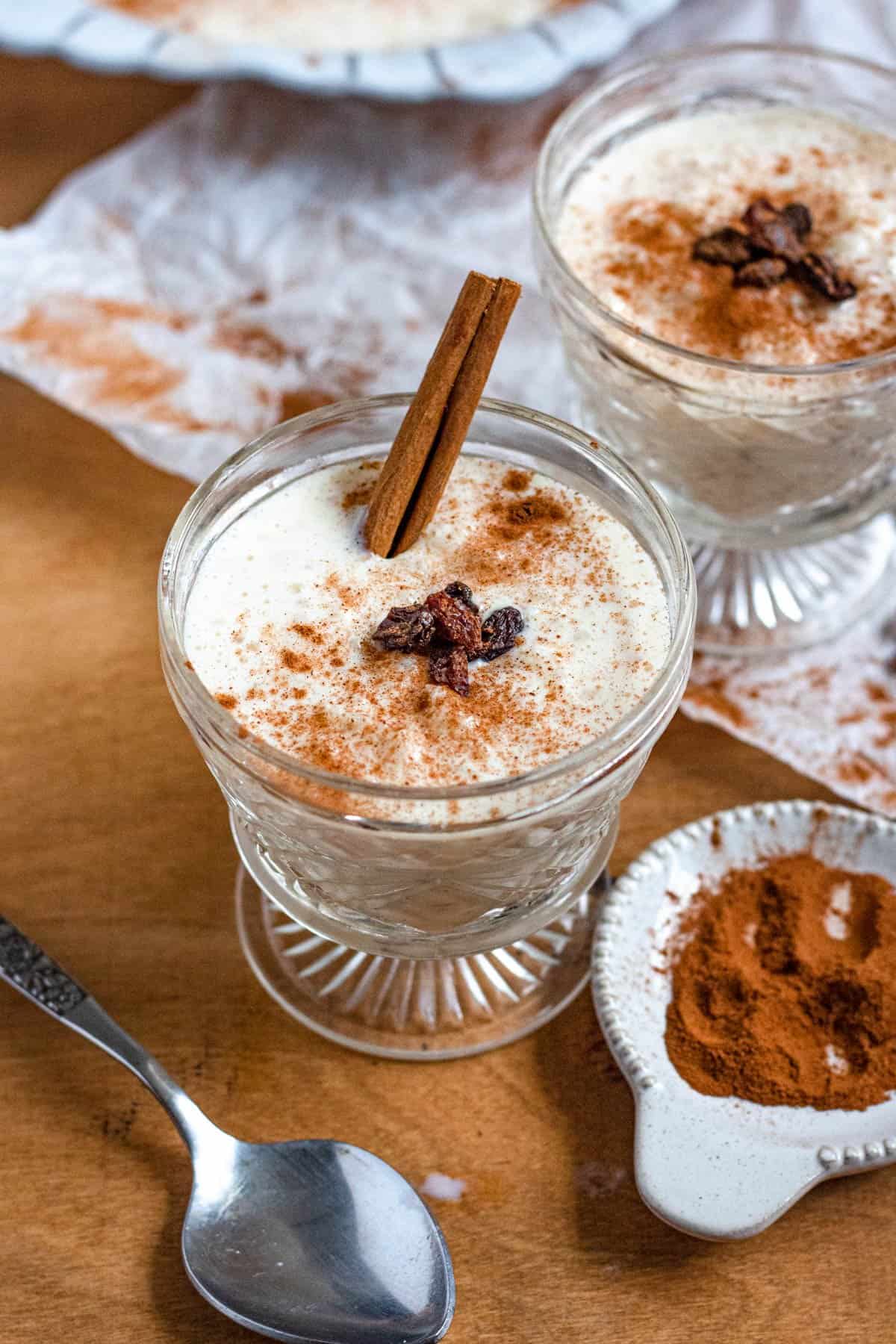 Glass cups of the dessert garnished with cinnamon sticks and raisins. 