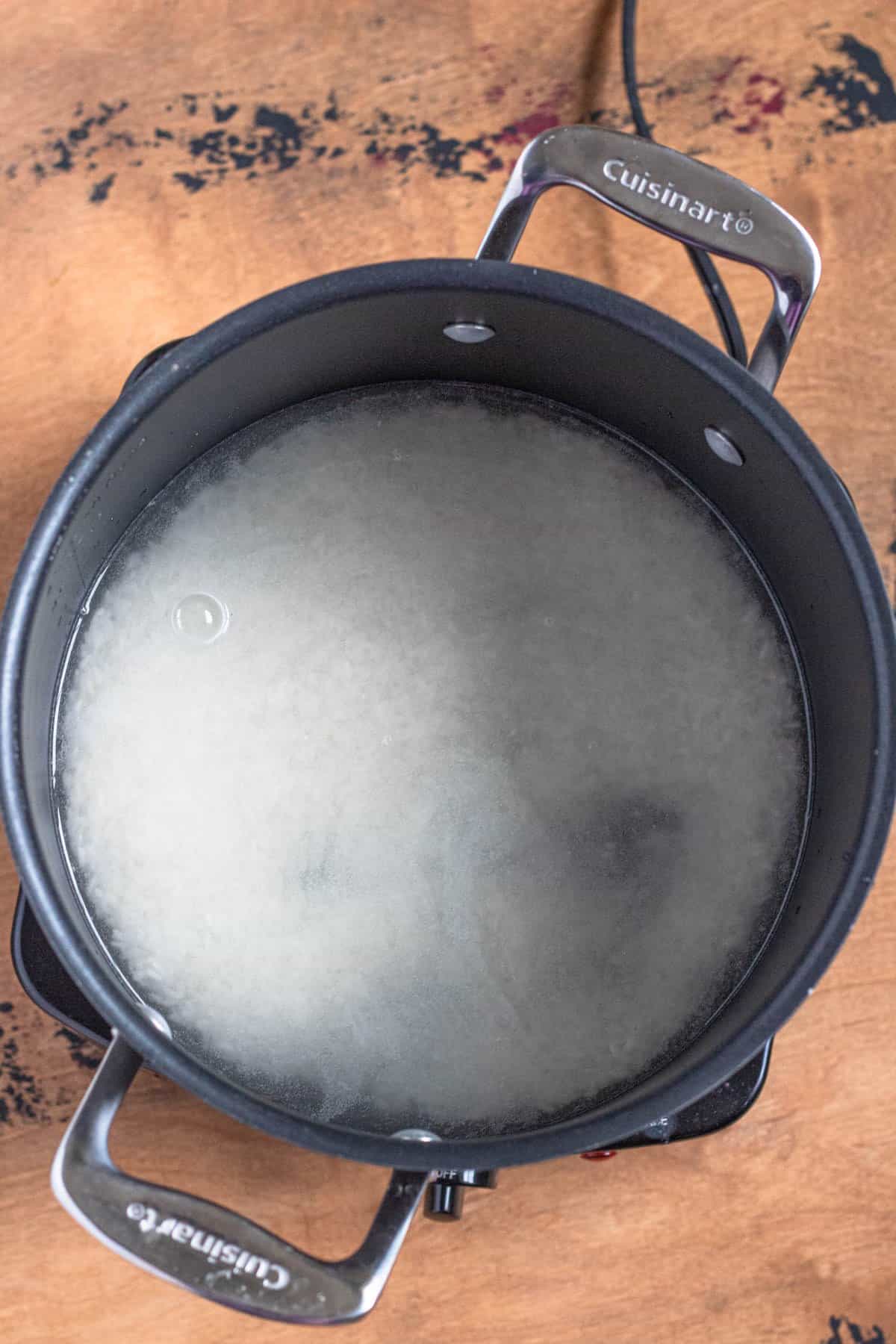 Water and rice with salt in a pan. 