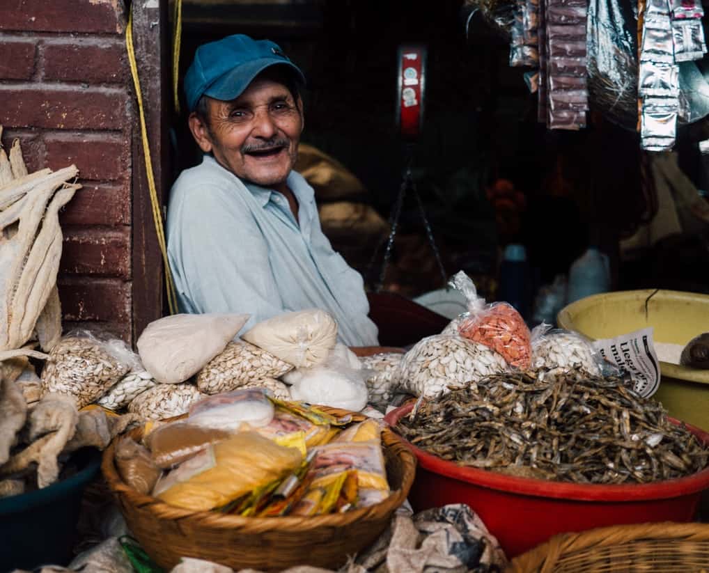 Smiling man sitting in front of his ingredients for sale. 